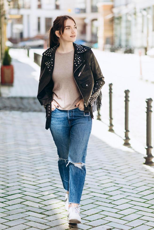 fille marchant dans la rue, vêtue d'une veste en cuir cool photo