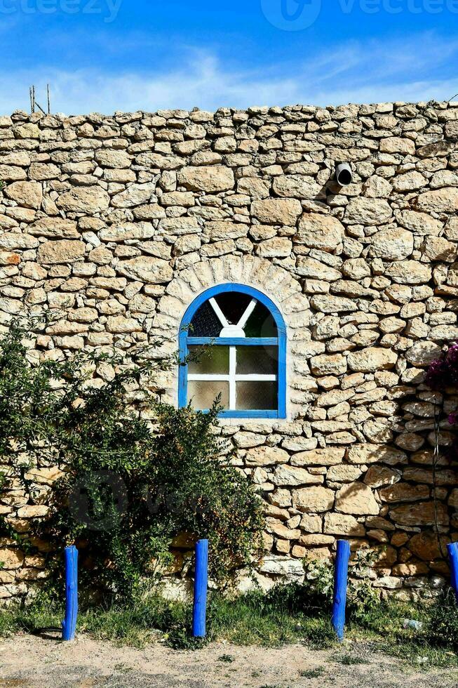 une pierre mur avec une bleu fenêtre et une bleu pôle photo