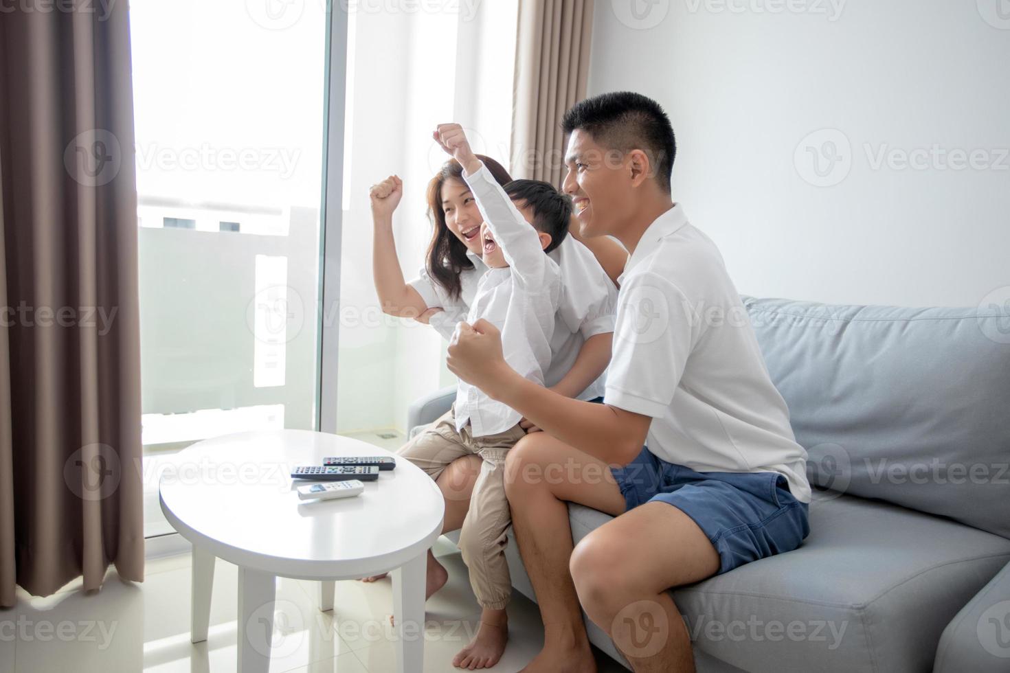 famille excitée et heureuse avec les bras levés en regardant la télévision à la maison photo