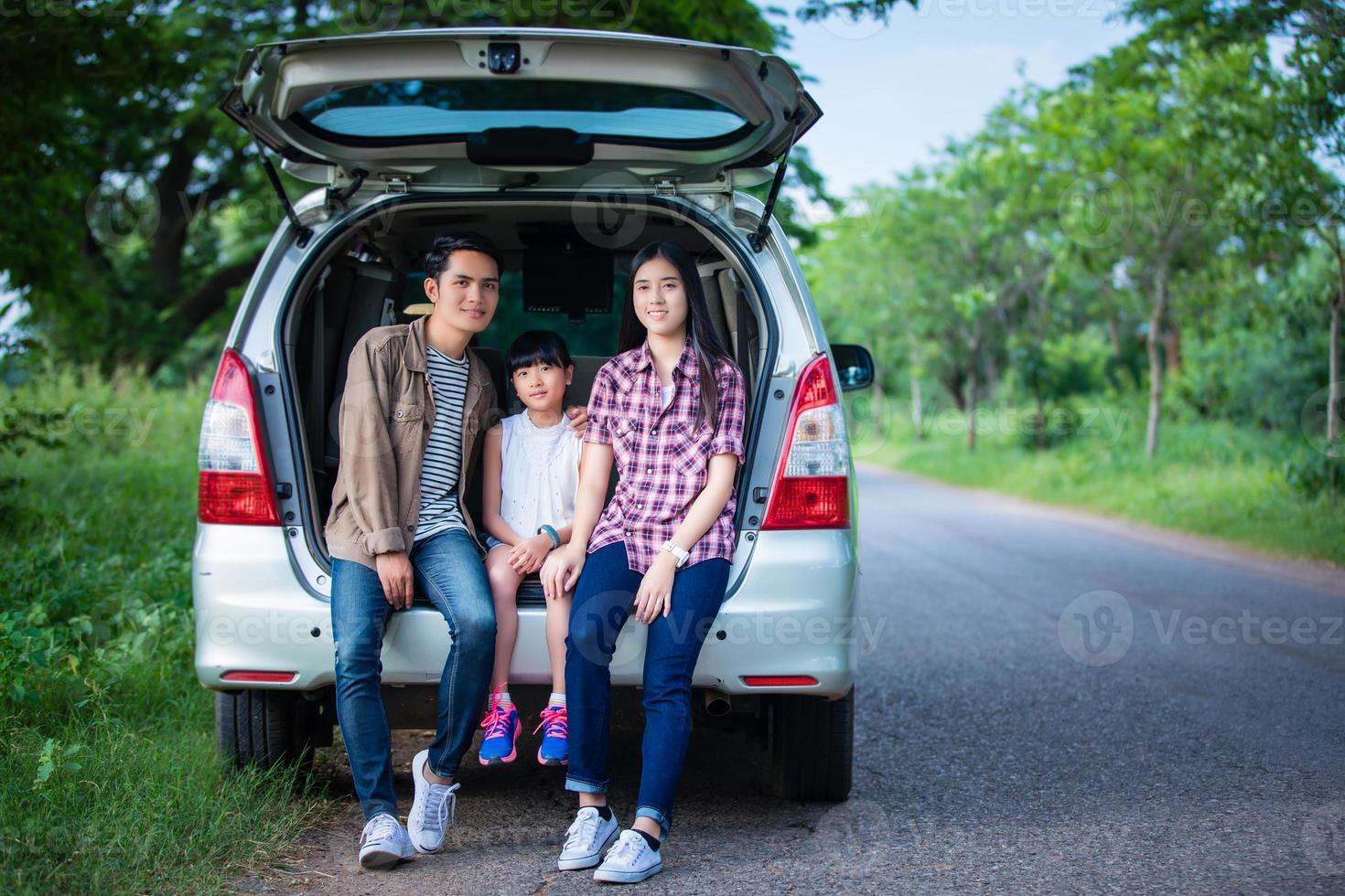 heureuse petite fille avec une famille asiatique assise dans la voiture pour profiter d'un voyage sur la route et de vacances d'été en camping-car photo