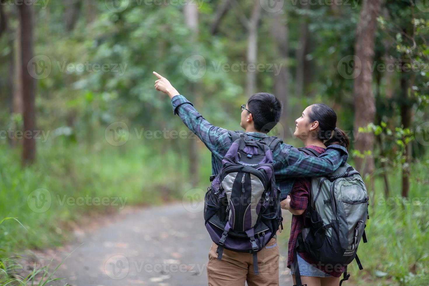 groupe asiatique de jeunes faisant de la randonnée avec des sacs à dos d'amis marchant ensemble et regardant la carte et prenant un appareil photo au bord de la route et ayant l'air heureux, détendez-vous en voyage de concept de vacances