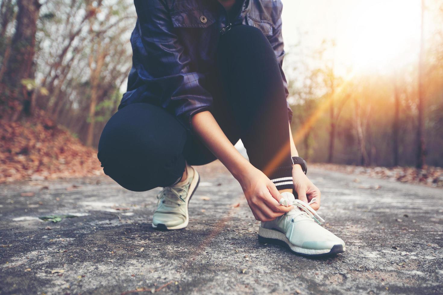 femme attachant des lacets de chaussures pour un coureur de fitness sportif se préparant à faire du jogging à l'extérieur sur un chemin forestier à la fin de l'été ou à l'automne. photo