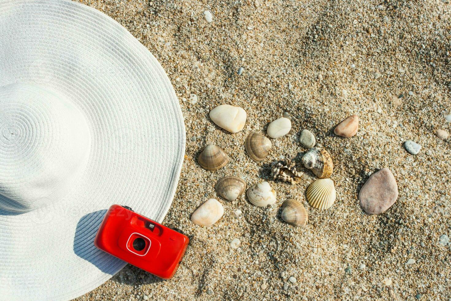 blanc chapeau, une rouge caméra et coquilles sur le le sable photo
