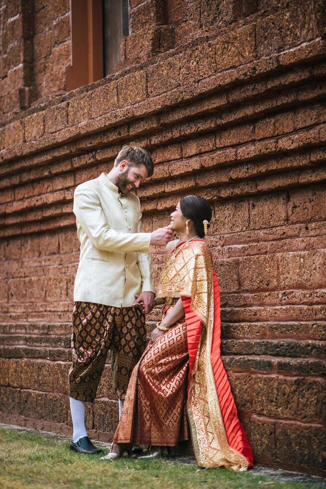 la mariée asiatique et le marié caucasien passent un moment romantique avec une robe thaïlandaise photo