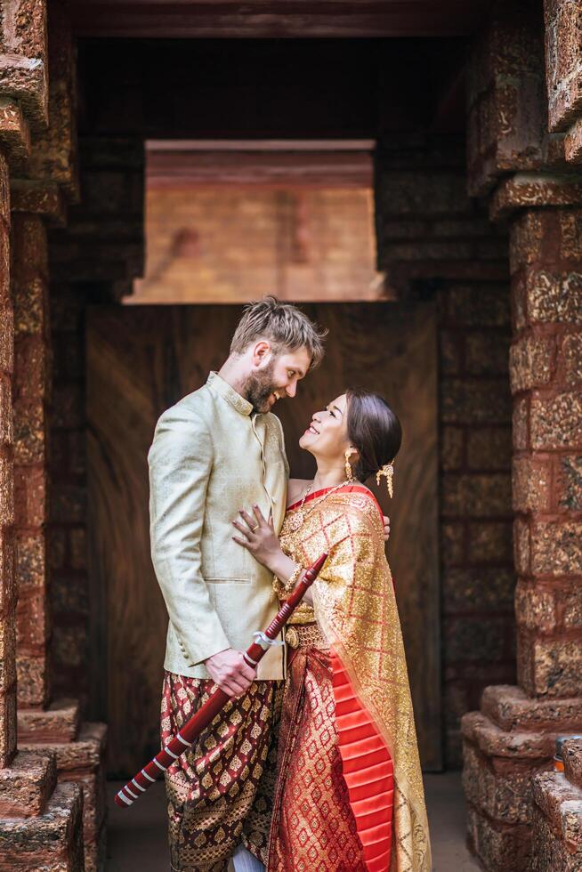 la mariée asiatique et le marié caucasien passent un moment romantique avec une robe thaïlandaise photo