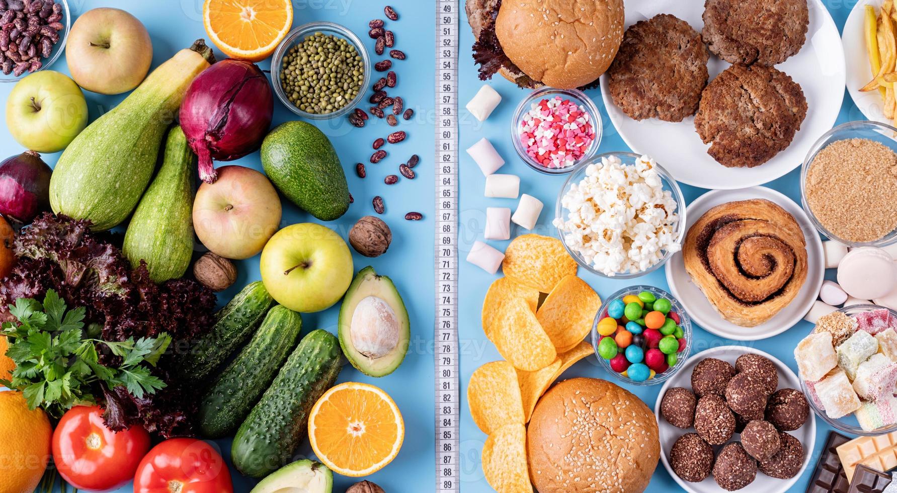 fruits et légumes vs bonbons et restauration rapide vue de dessus à plat sur fond bleu photo