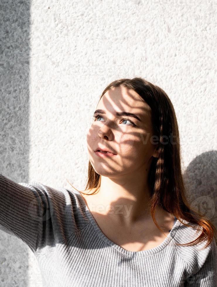 portrait d'une belle jeune femme avec un motif d'ombre sur le visage et le corps sous forme de feuille de palmier photo