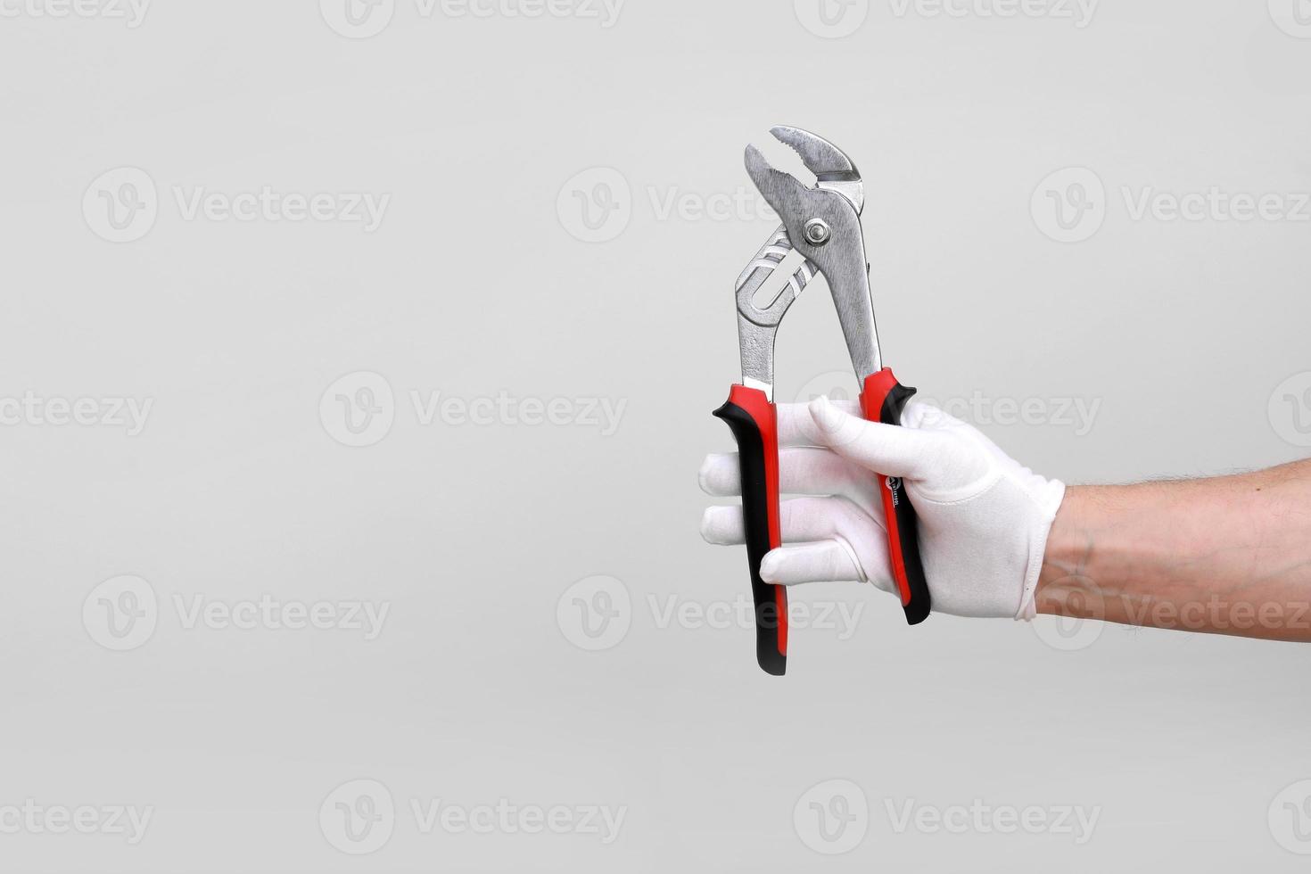 Mans main dans un gant blanc surélevé tenant une pince à outils noire et rouge, coupe-fil. isolé sur fond blanc. forme ouverte, propre, prête à découper. espace de copie de maquette photo