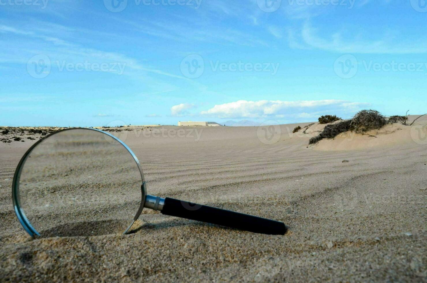 une grossissant verre dans le le sable photo