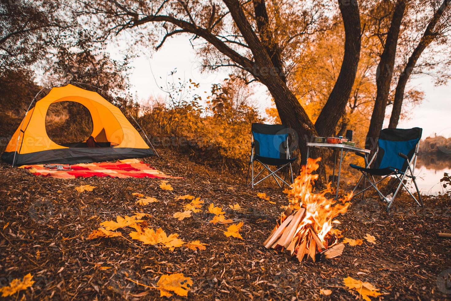 camping place d'automne avec feu de joie et chaises portables photo