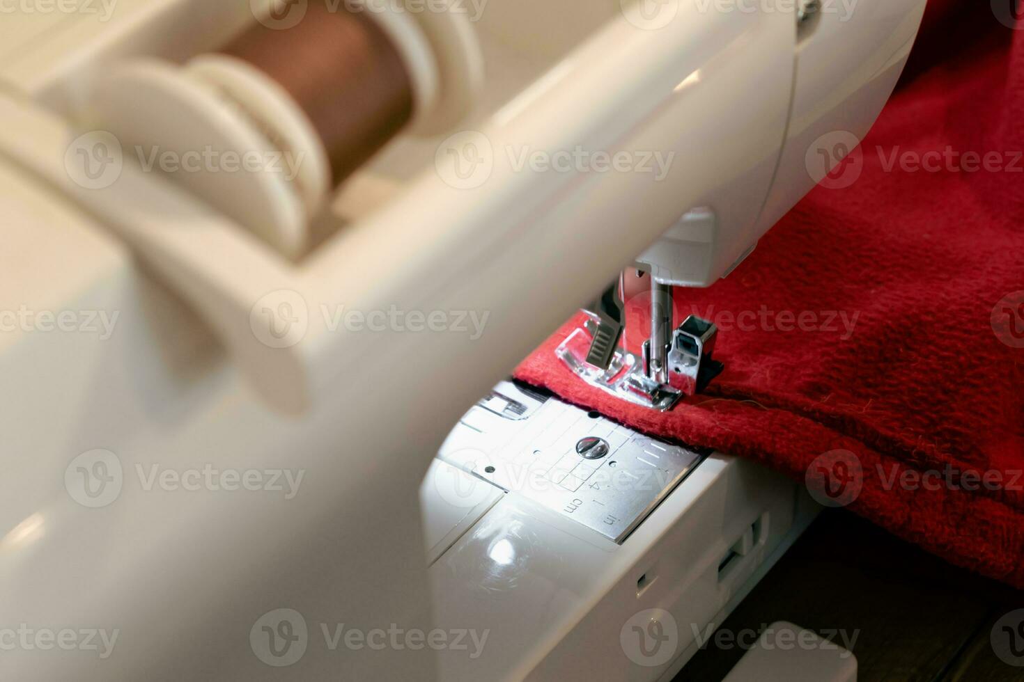 homme en utilisant une couture machine avec une rouge vêtement, pour réparation travail, personnalisation, création, recyclage photo