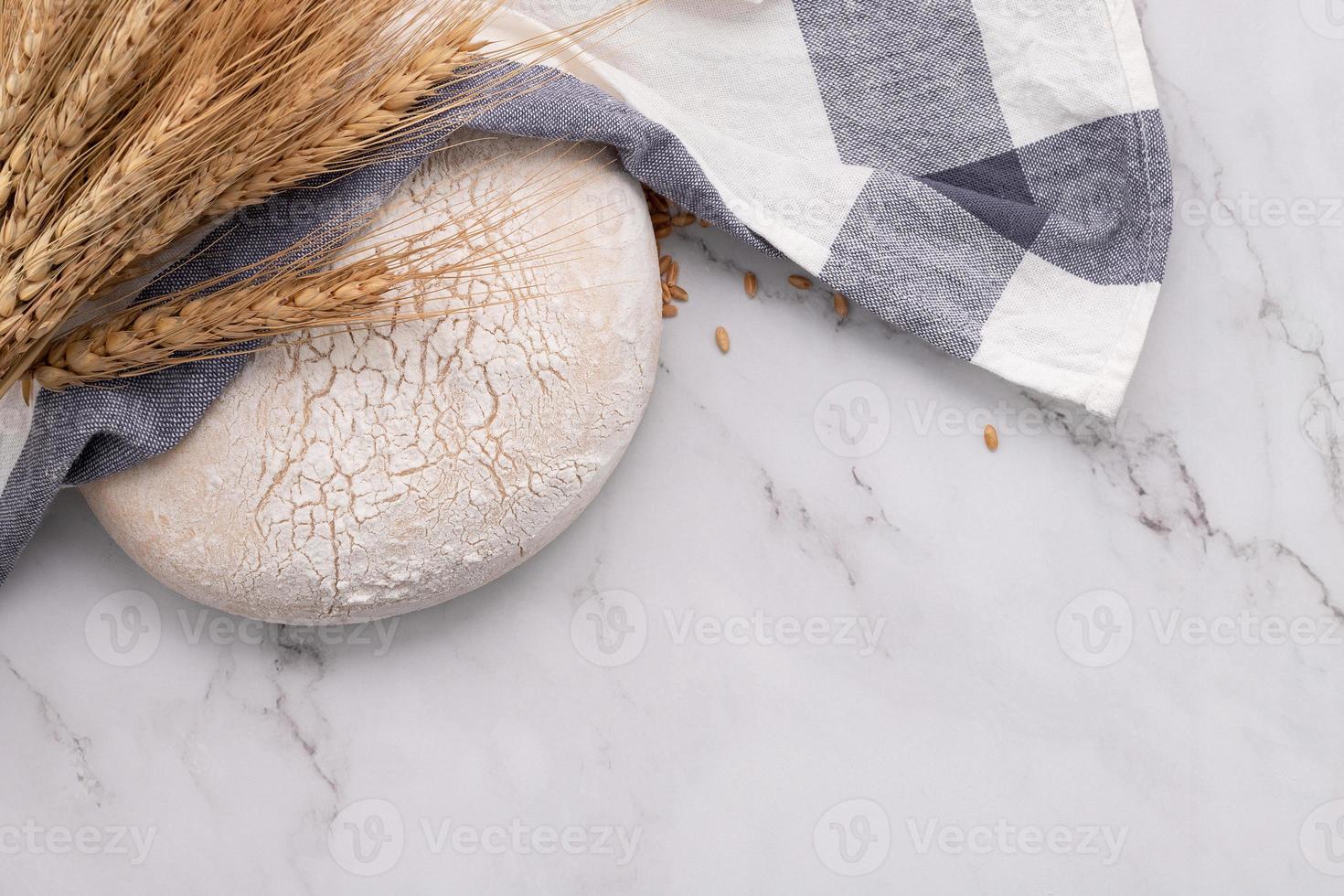 pâte à levure fraîche faite maison reposant sur une table en marbre avec des épis de blé et un rouleau à pâtisserie. photo