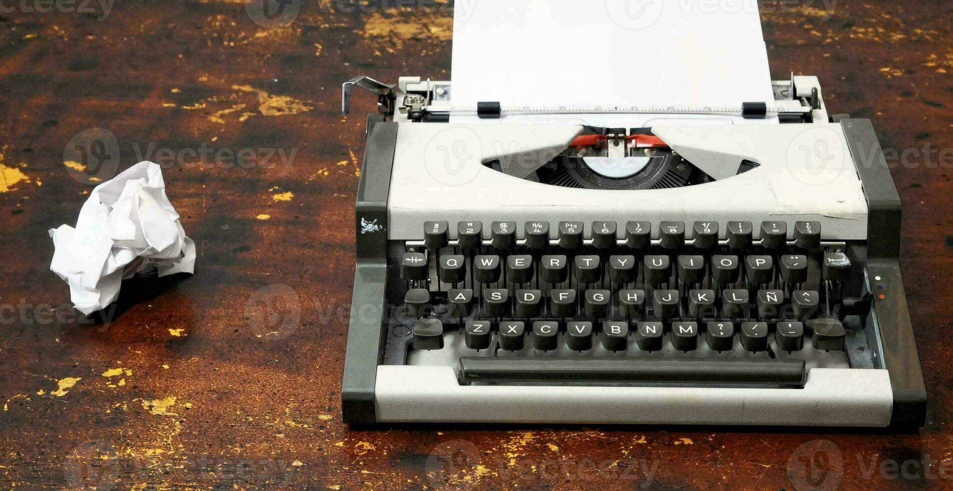 un vieux machine à écrire avec une froissé papier sur le côté photo
