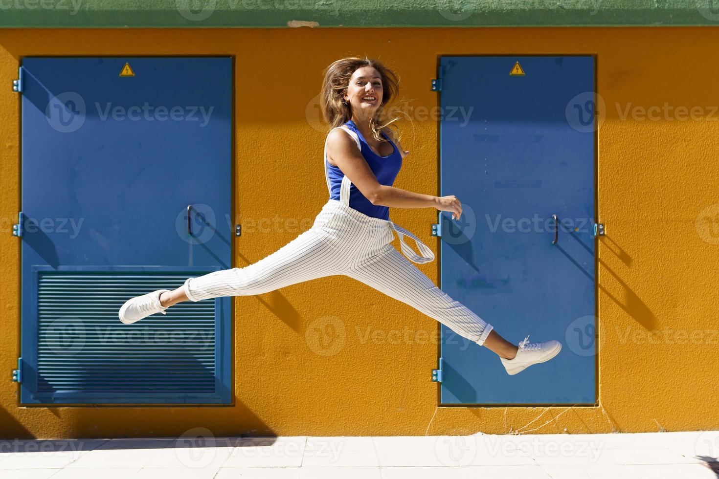 Happy young woman jumping in urban background photo