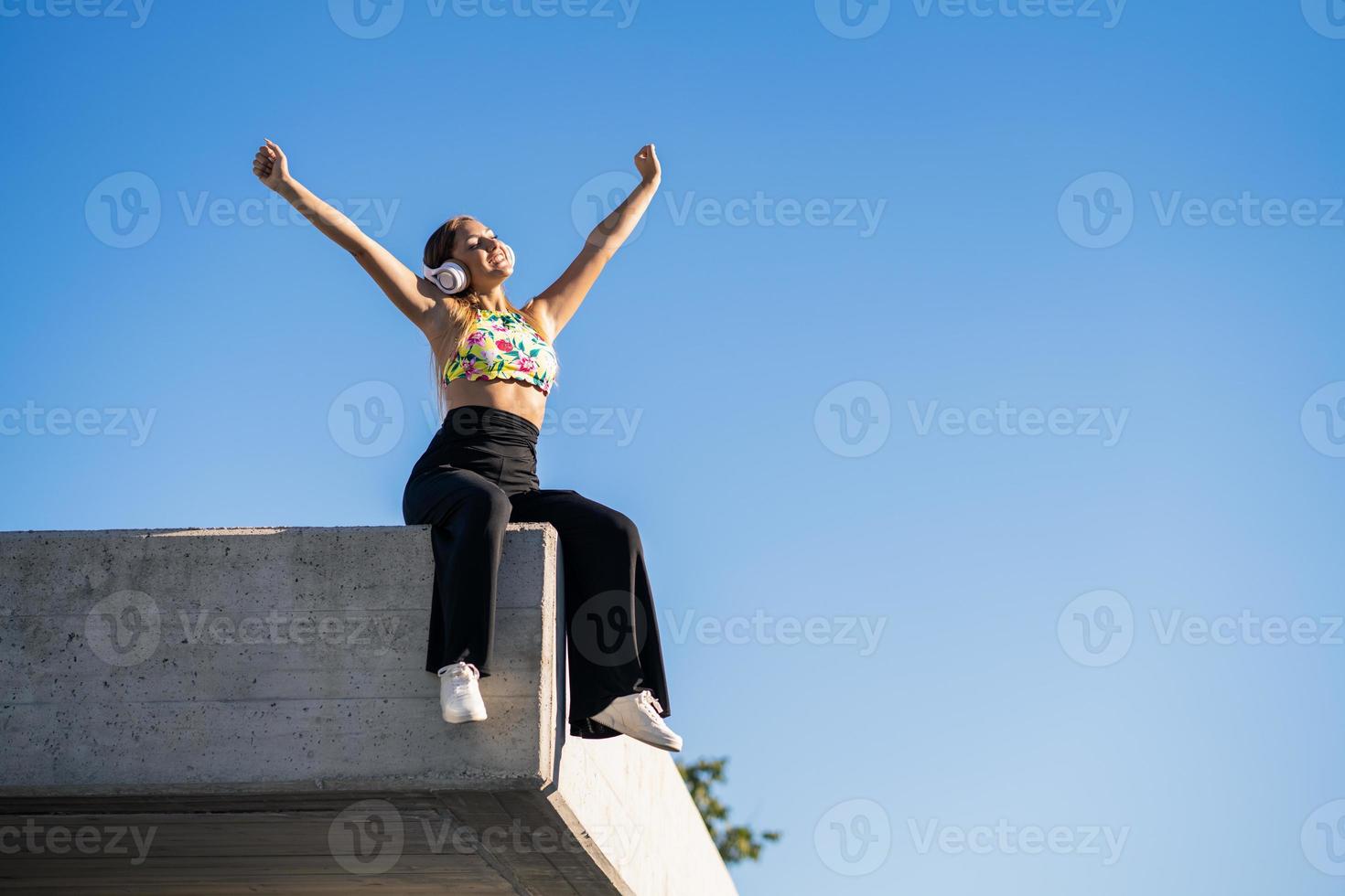 Jeune femme ouvrant les bras portant des écouteurs à l'extérieur photo