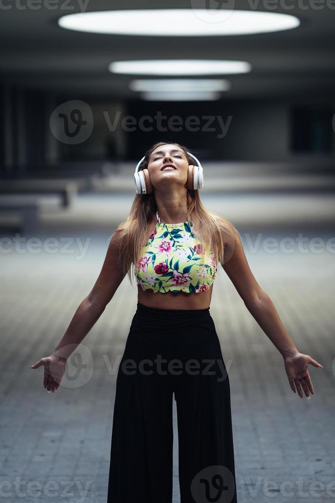 Jeune femme ouvrant les bras portant des écouteurs à l'extérieur photo