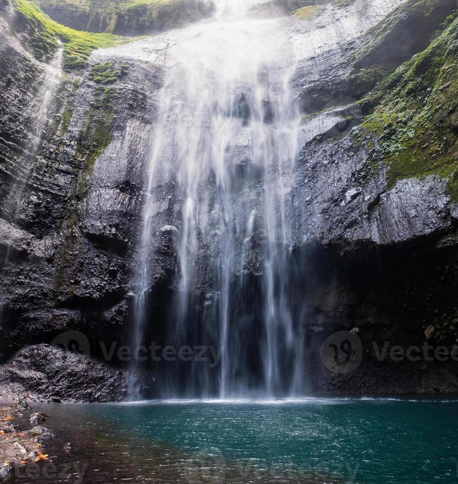cascade majestueuse qui coule sur une falaise rocheuse dans la forêt tropicale photo