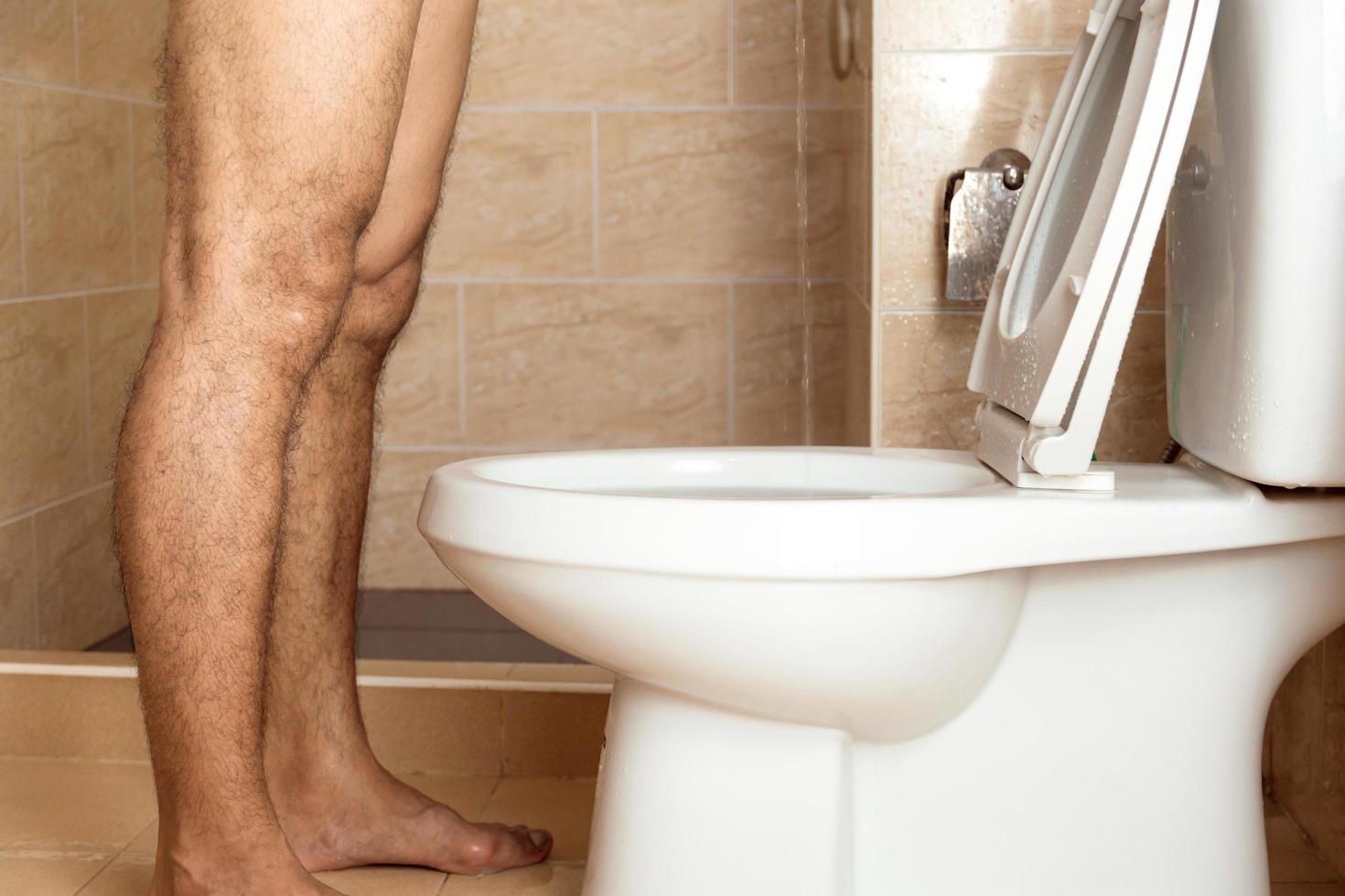 un homme debout urine dans les toilettes. photo