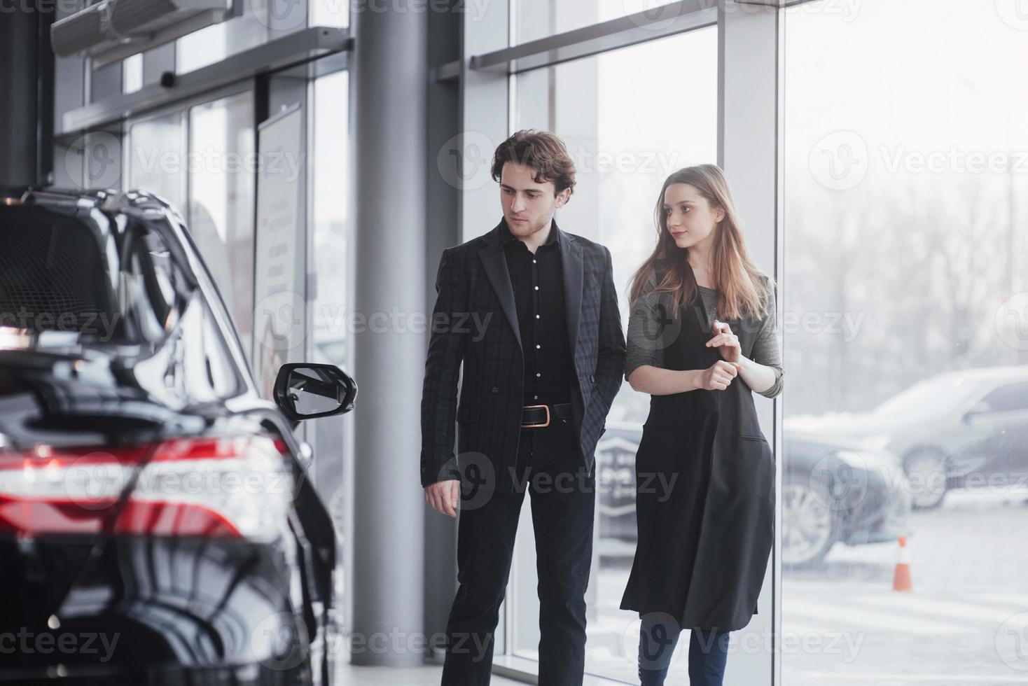 c'est la seule voiture que je veux. beau jeune couple debout chez le concessionnaire choisissant la voiture à acheter photo