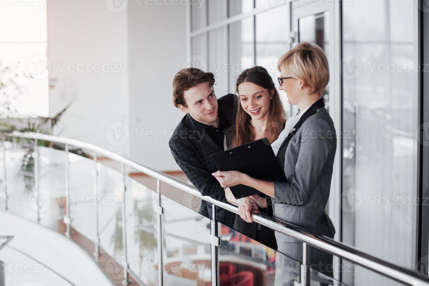 jeune équipe professionnelle. groupe de jeunes gens modernes en tenue décontractée intelligente ayant une réunion de remue-méninges tout en se tenant derrière le mur de verre dans le bureau de création photo