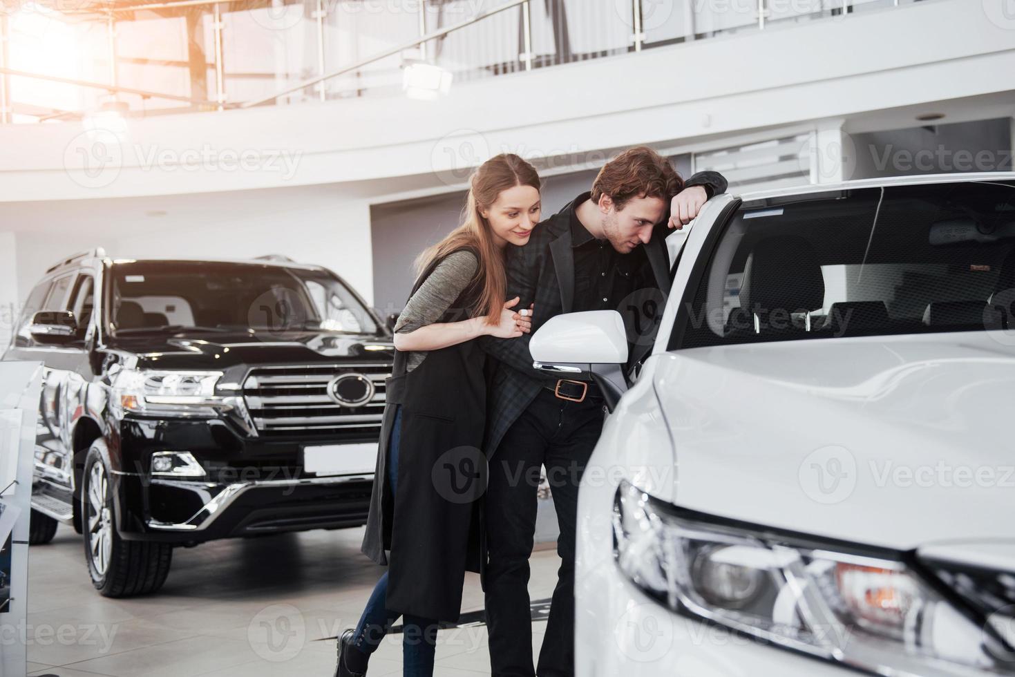 c'est la seule voiture que je veux. beau jeune couple debout chez le concessionnaire choisissant la voiture à acheter photo