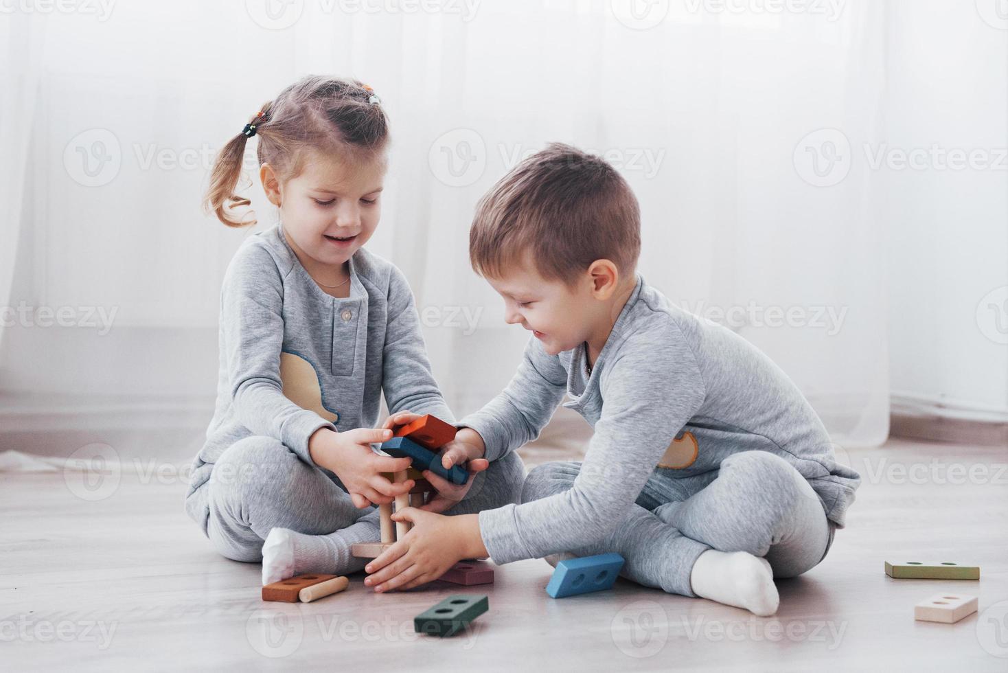les enfants jouent avec un créateur de jouets sur le sol de la chambre des enfants. deux enfants jouant avec des blocs colorés. jeux éducatifs de maternelle photo