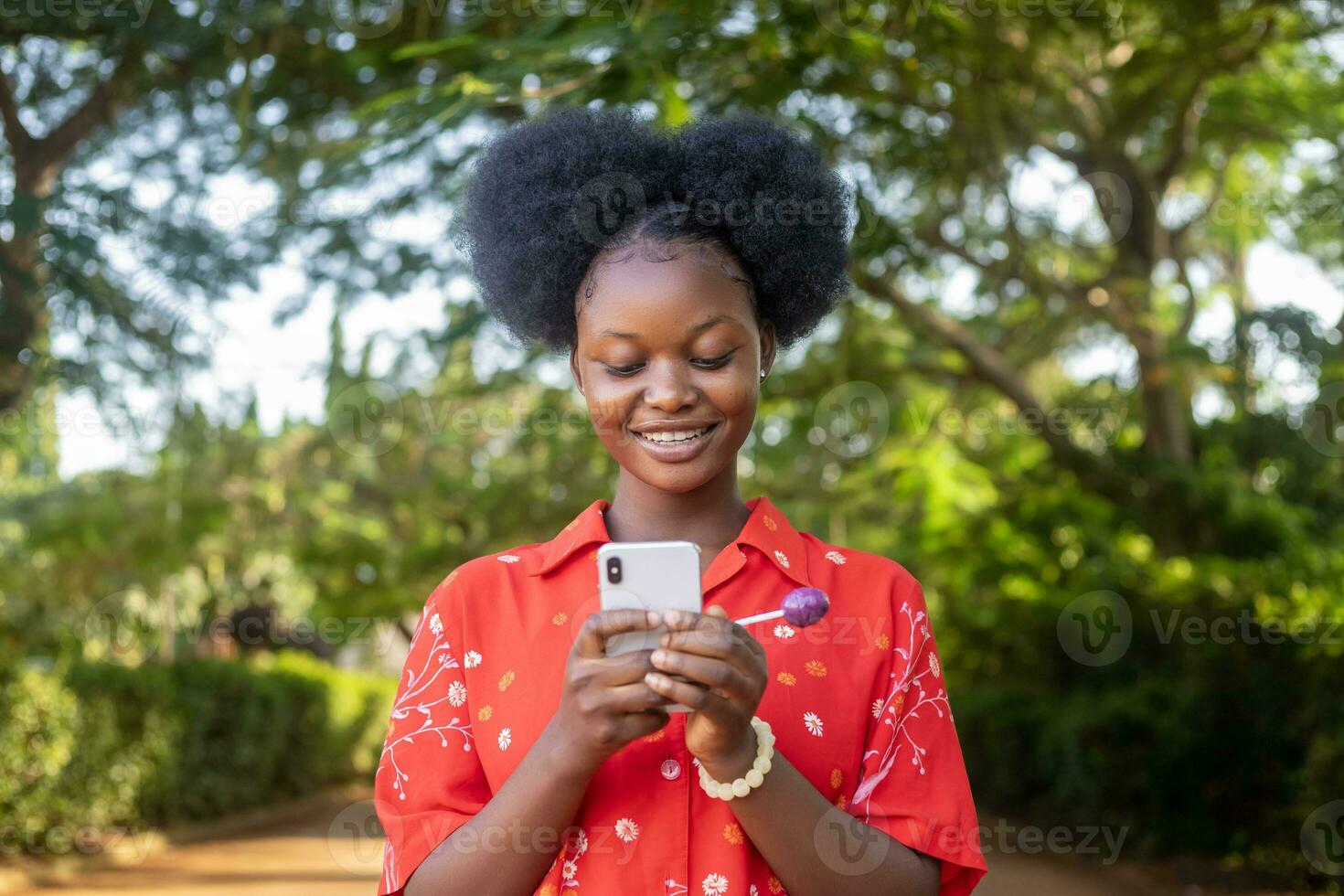 jolie noir femme Regardez très excité et se réjouit tandis que à la recherche à sa téléphone photo