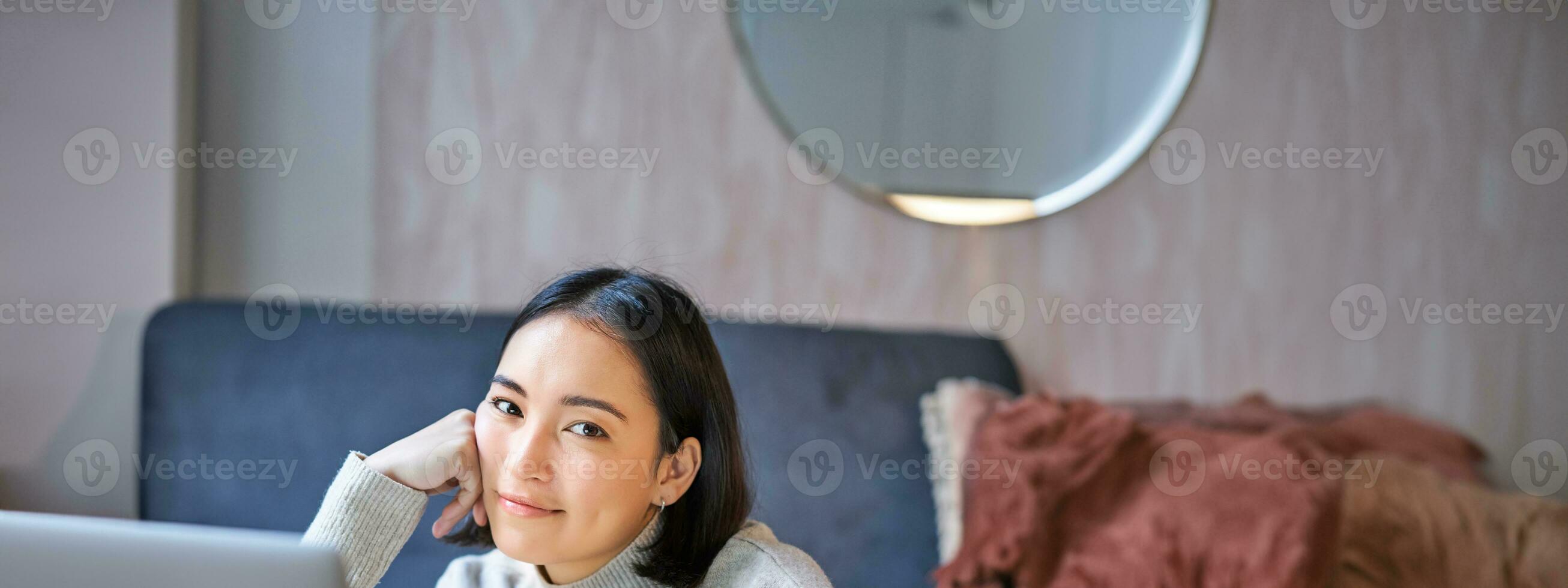 verticale coup de Jeune asiatique femme à la recherche fatigué, souriant avec épuisé expression, travail de Accueil sur sa portable photo