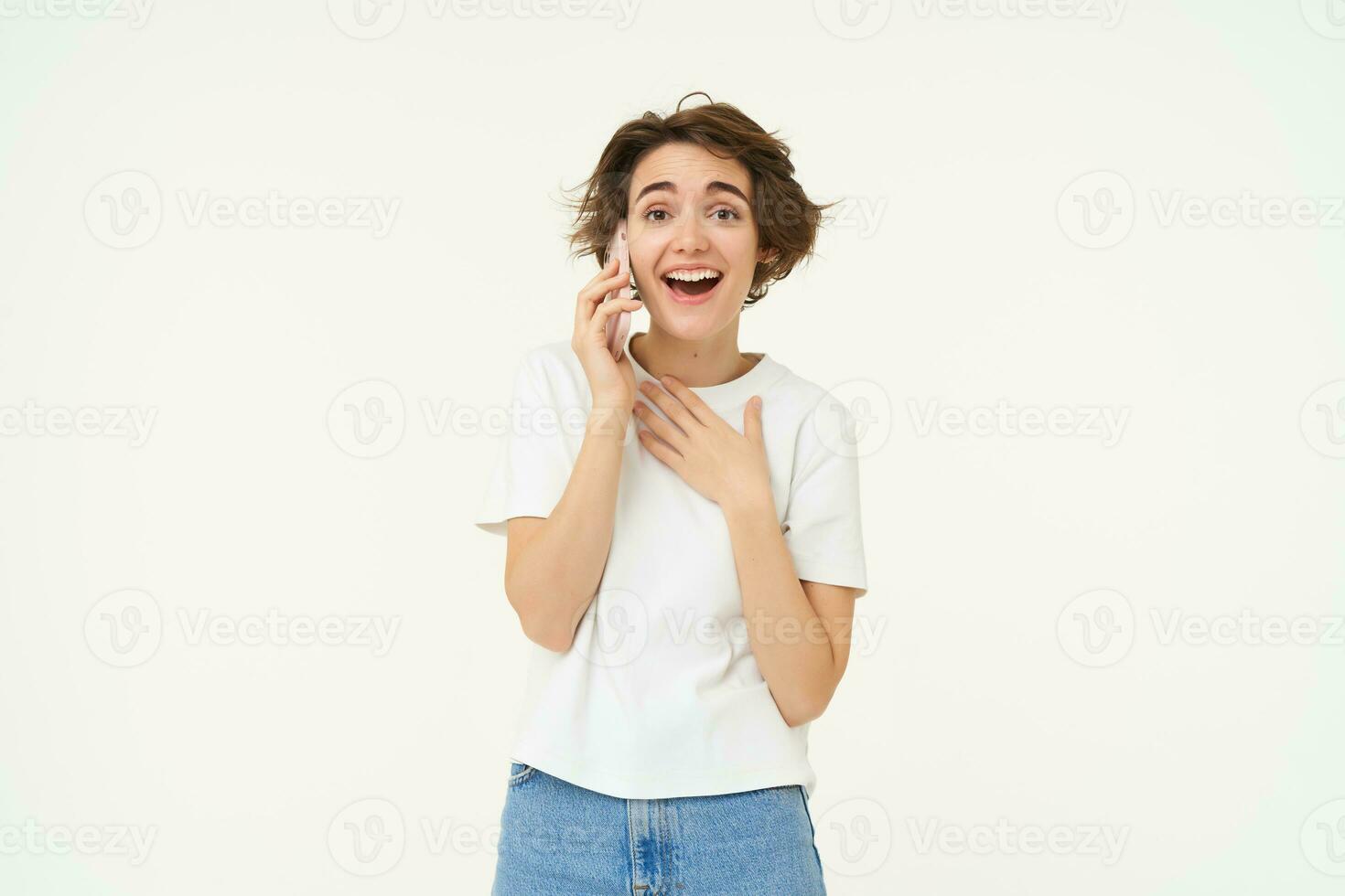 portrait de bavard Jeune femme parlant sur mobile téléphone, en riant et souriant, répondre Téléphone avec surpris affronter, permanent plus de blanc Contexte photo