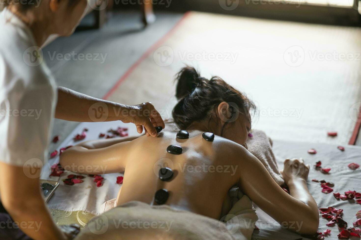 massage et spa traitement relaxant du syndrome de bureau en utilisant le style de massage thaï traditionnel aux pierres chaudes. asain femme masseuse faisant des massages traite les maux de dos, les douleurs au bras, le stress pour les femmes fatiguées du travail. photo