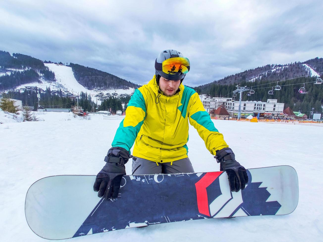 homme avec snowboard assis à la colline enneigée photo