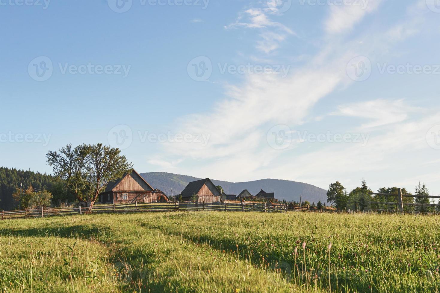 maisons de village sur les collines aux vertes prairies en journée d'été. maison des bergers dans les montagnes des carpates photo