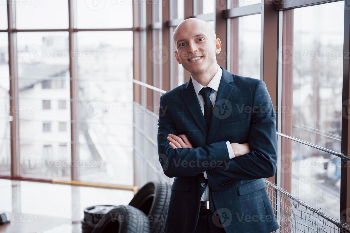 Portrait of smiling young businessman standing bras croisés s'appuyant sur placard in office photo