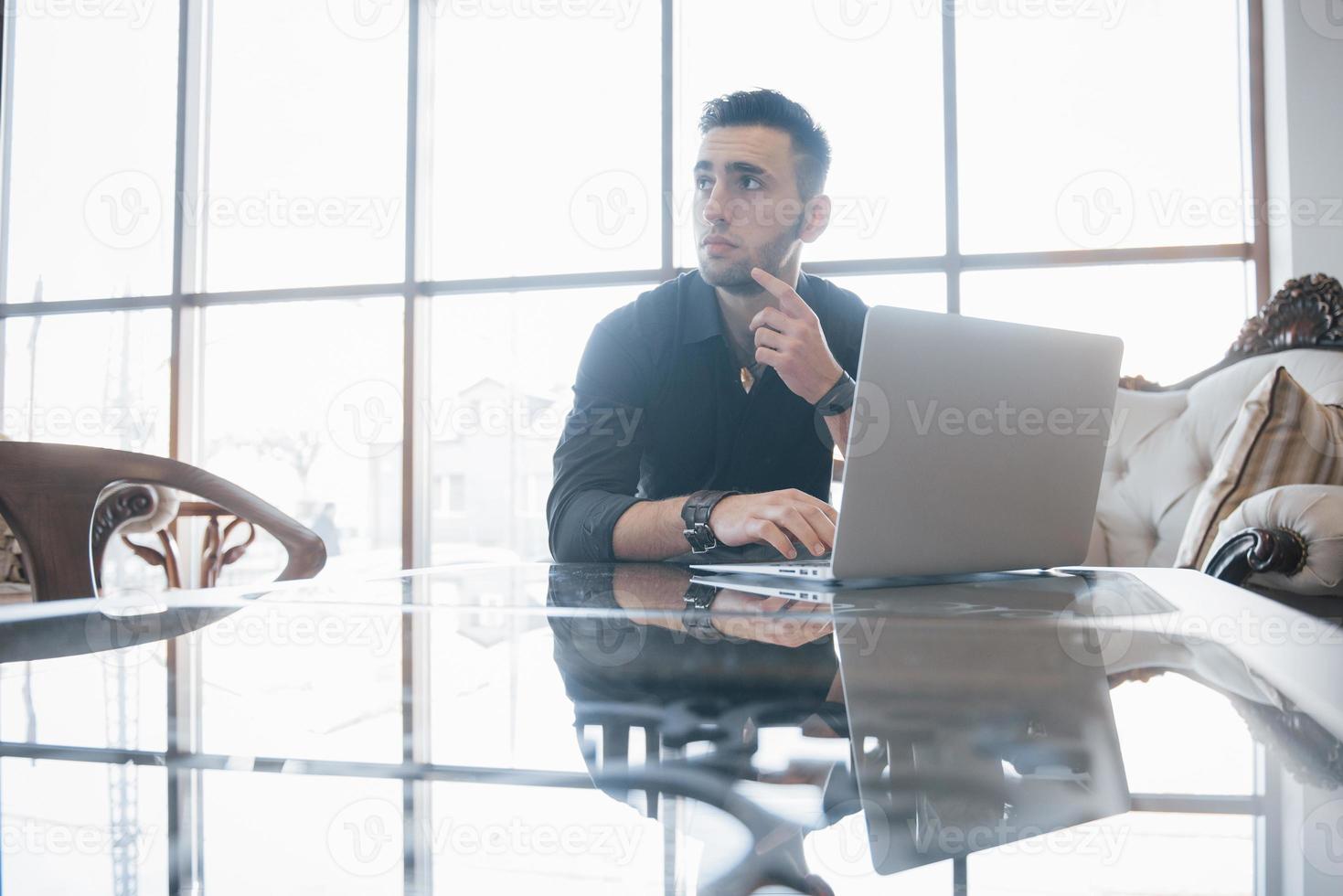 conçu un jeune homme travaillant sur un ordinateur portable alors qu'il était assis sur son lieu de travail au bureau photo