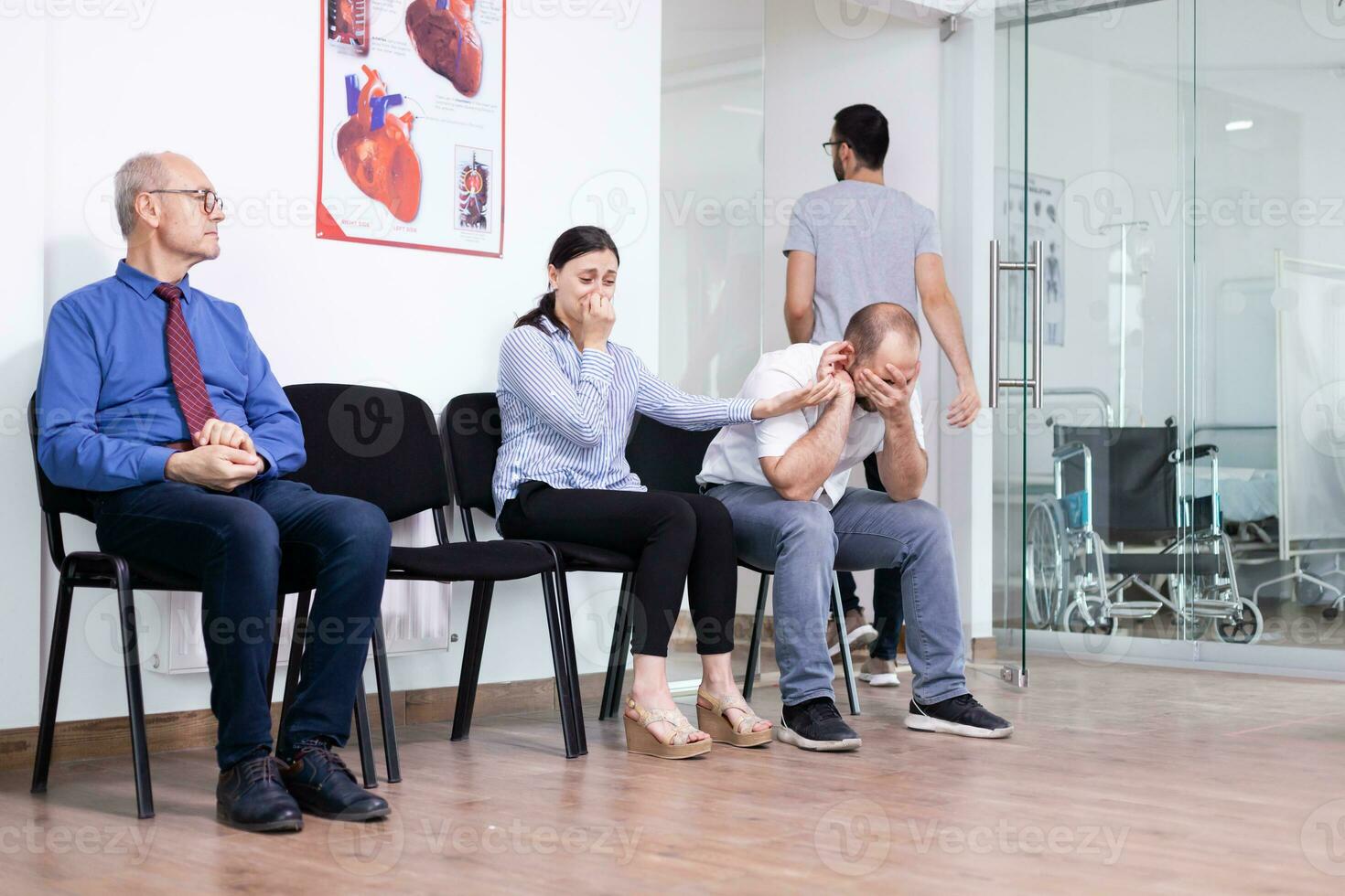 Jeune homme cynique en portant épouse main dans hôpital couloir après défavorable nouvelles de médical spécialiste. stressé homme et femme pendant médical rendez-vous. homme en quittant clinique. photo