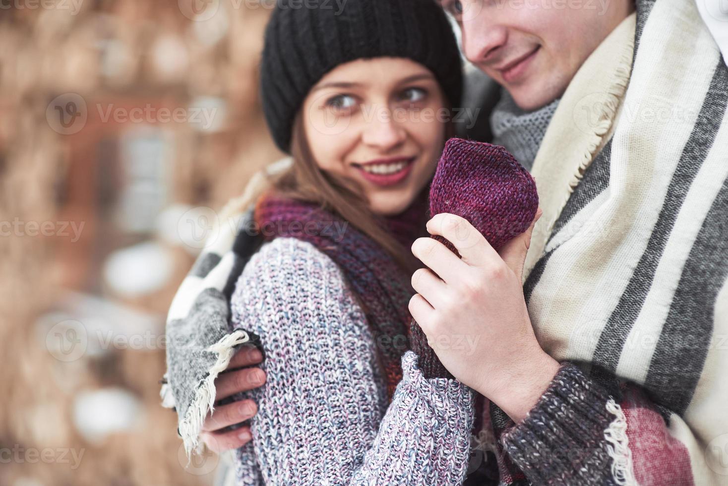 portrait à la taille d'un jeune homme et d'une femme insouciants embrassant et souriant. ils se tiennent dans la forêt d'hiver et regardent la caméra avec bonheur photo