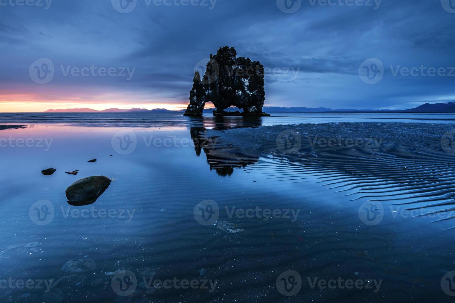 est un rocher spectaculaire dans la mer sur la côte nord de l'Islande. les légendes disent que c'est un troll pétrifié. sur cette photo hvitserkur se reflète dans l'eau de mer après le coucher du soleil de minuit