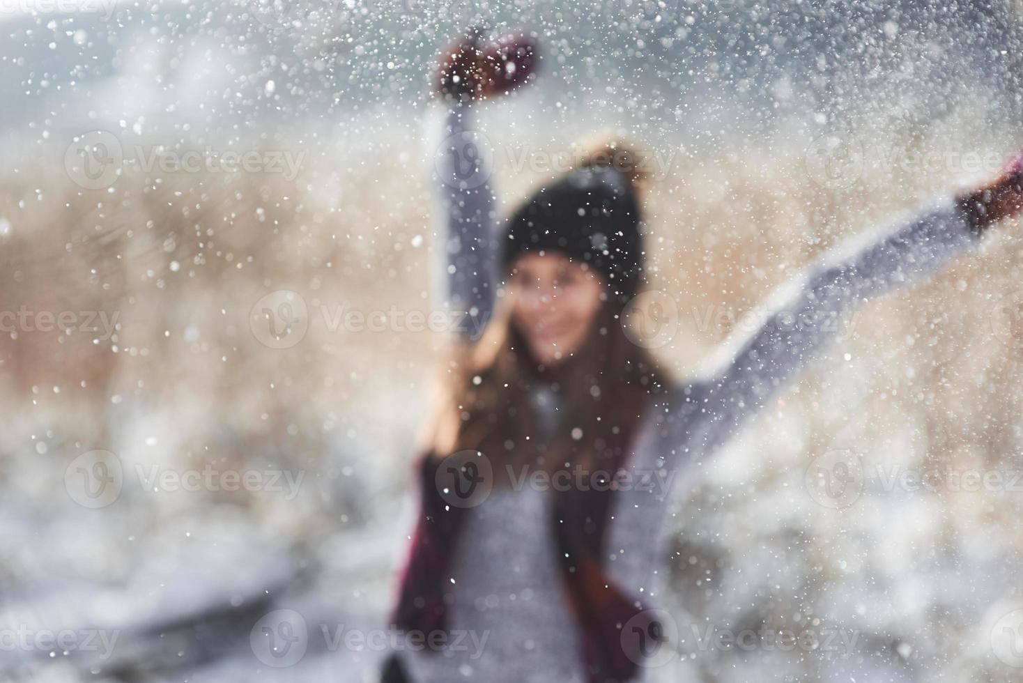 fille d'hiver de beauté poudrerie dans le parc d'hiver glacial. en plein air. flocons de neige volants. journée ensoleillée. rétro-éclairé. joyeuse beauté jeune femme s'amusant dans le parc d'hiver. défocalisé photo