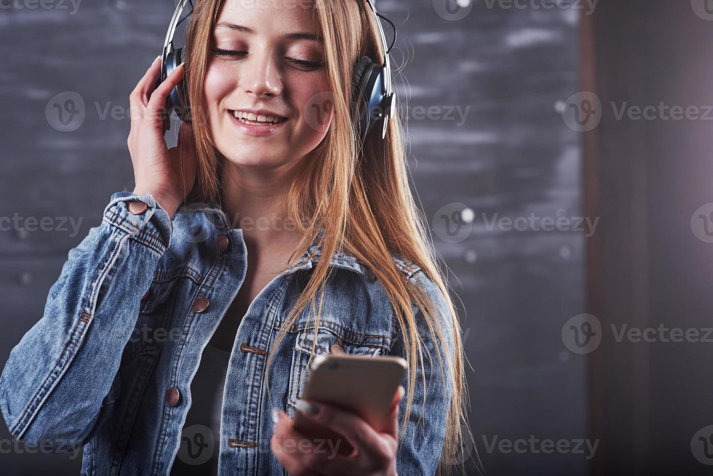 mode, vêtements, concept de personnes. gros plan séduisante jeune femme sexy avec une veste en jean. fille pose en studio écoute de la musique dans les écouteurs photo