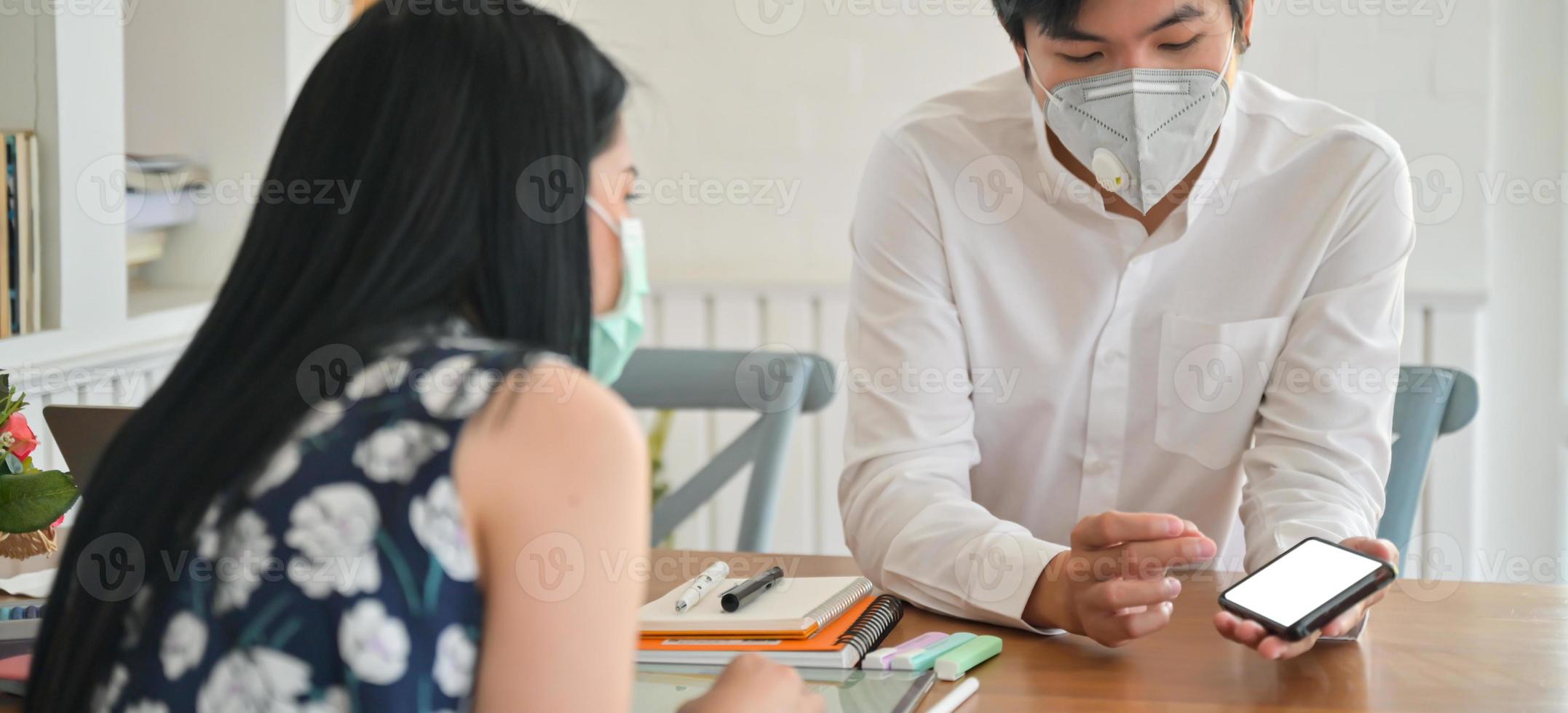 un agent d'assurance masculin portant un masque introduit un forfait d'assurance maladie contre les coronavirus avec un smartphone. photo