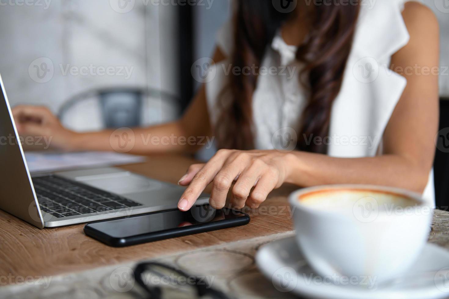 les femmes d'affaires utilisent un smartphone et un ordinateur portable pour travailler au bureau. photo