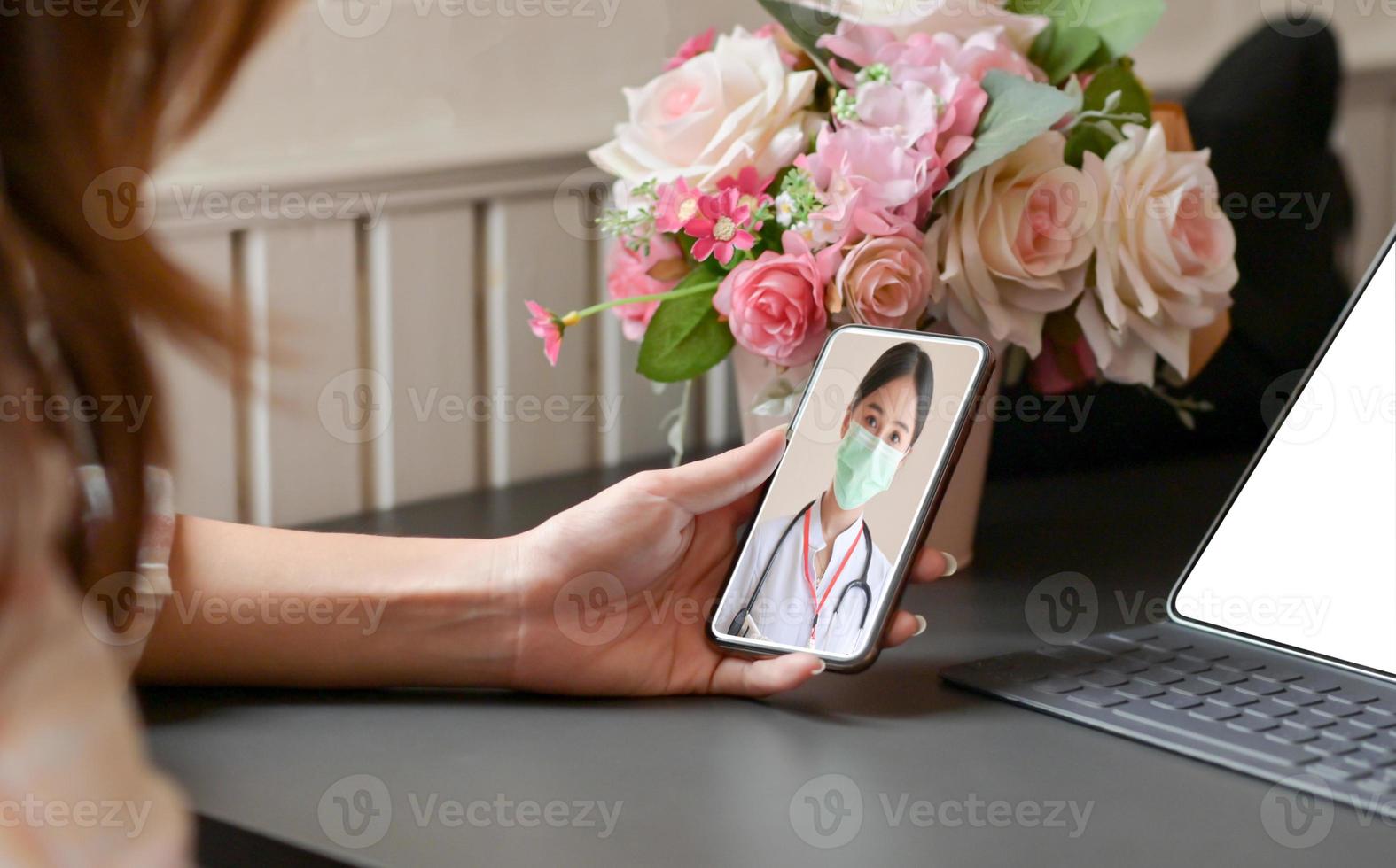 photo recadrée d'une jeune femme restée à la maison, elle utilise un smartphone pour consulter un médecin lors d'appels vidéo.