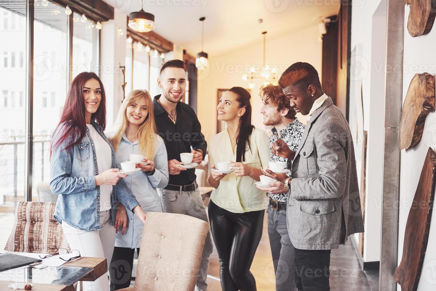 les jeunes gens d'affaires qui réussissent parlent et sourient pendant la pause-café au bureau photo