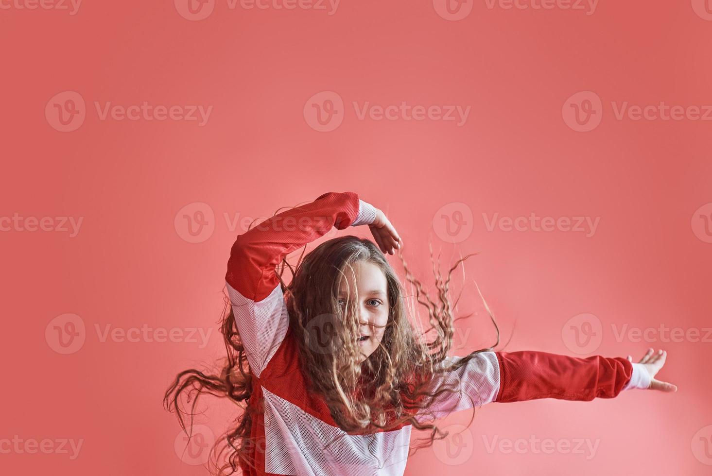 Jeune belle fille mignonne dansant sur fond rouge, adolescente moderne de style hip-hop mince sautant photo