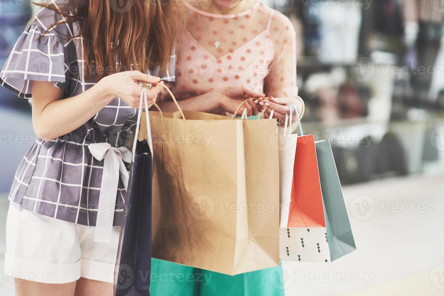 belle journée pour faire du shopping. deux belles femmes avec des sacs à provisions se regardant avec le sourire en marchant dans le magasin de vêtements photo
