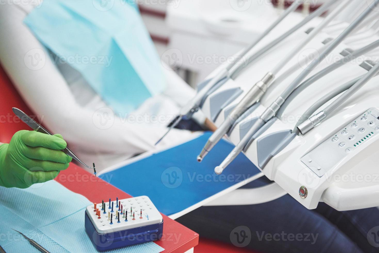 un patient dans une clinique dentaire est assis sur une chaise et le médecin prépare les outils pour le traitement photo