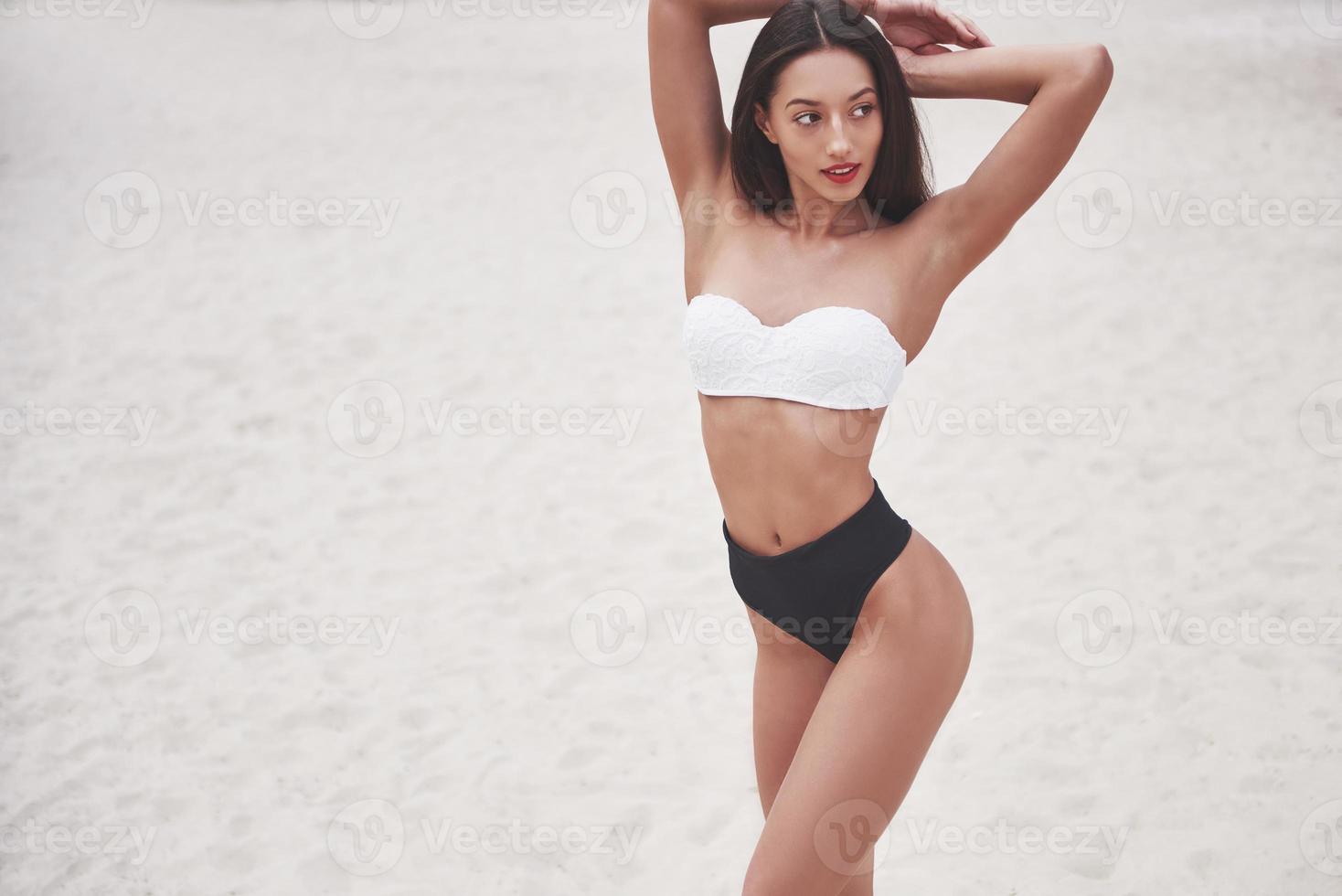 belle fille de luxe mince en bikini sur la plage de sable sur une île tropicale. corps bronzé sexy et silhouette parfaite photo