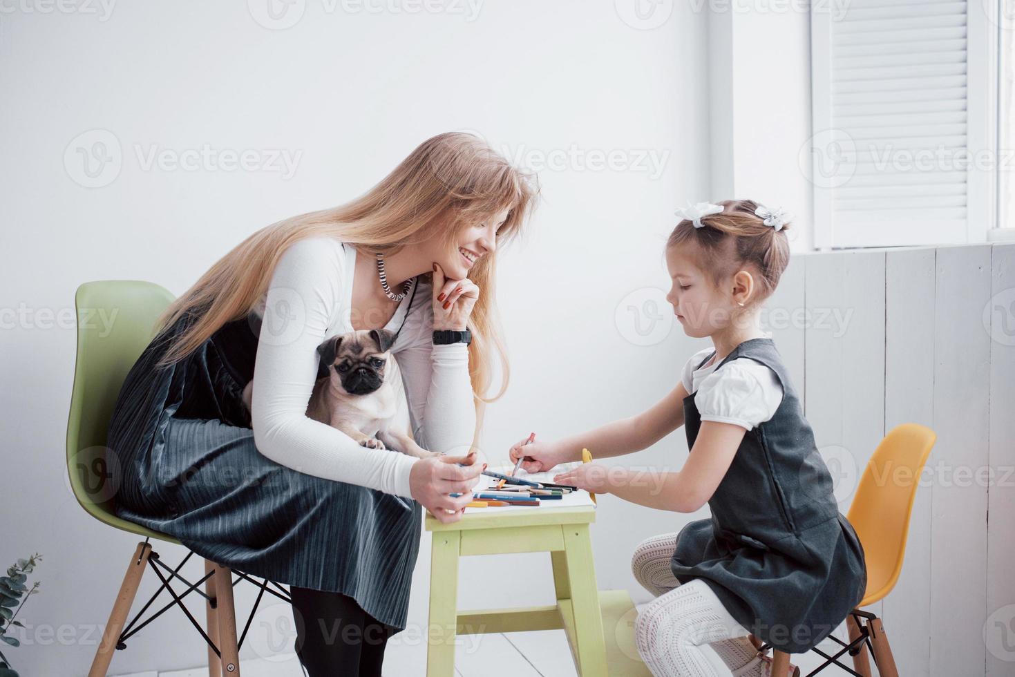 les dessins de la mère et de l'enfant fille sont engagés dans la créativité à la maternelle. petit carlin avec eux photo