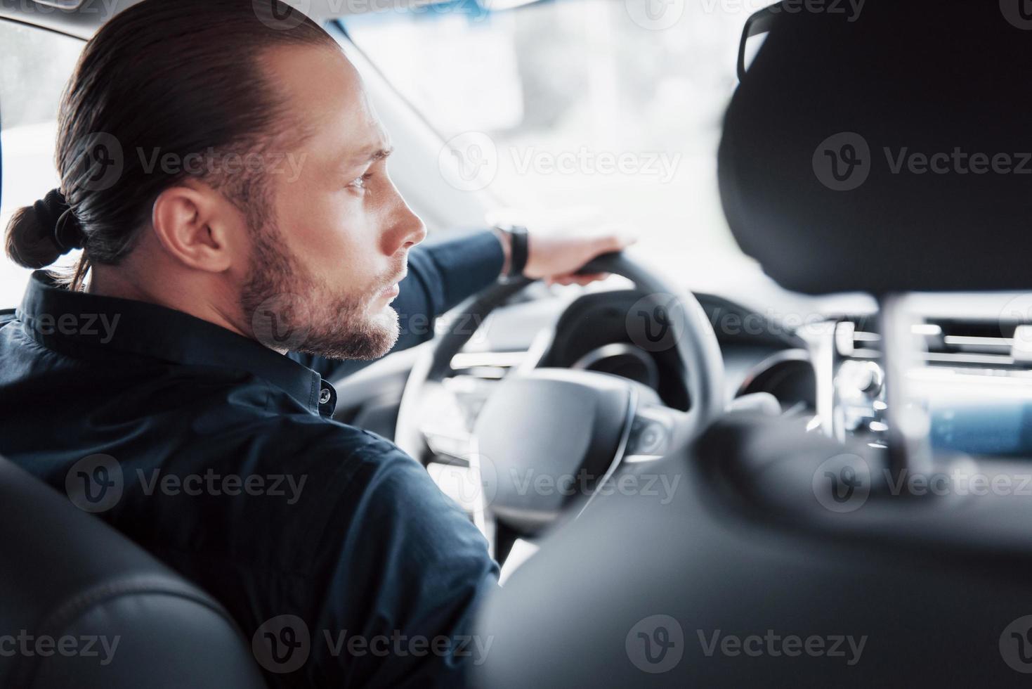 jeune homme d'affaires confiant assis au volant de sa nouvelle voiture photo