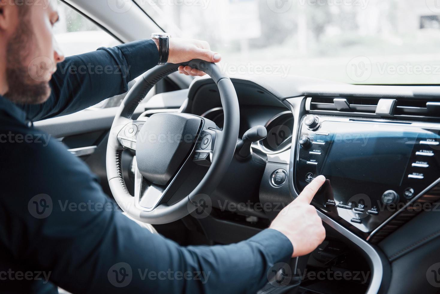 jeune homme d'affaires confiant assis au volant de sa nouvelle voiture photo